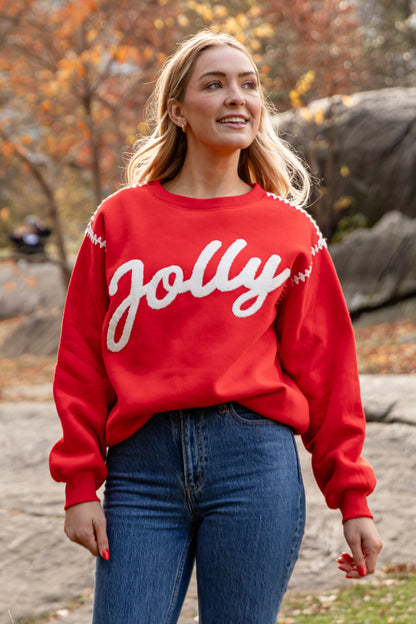 Woman wearing a red 'Jolly' sweater in an autumn park setting