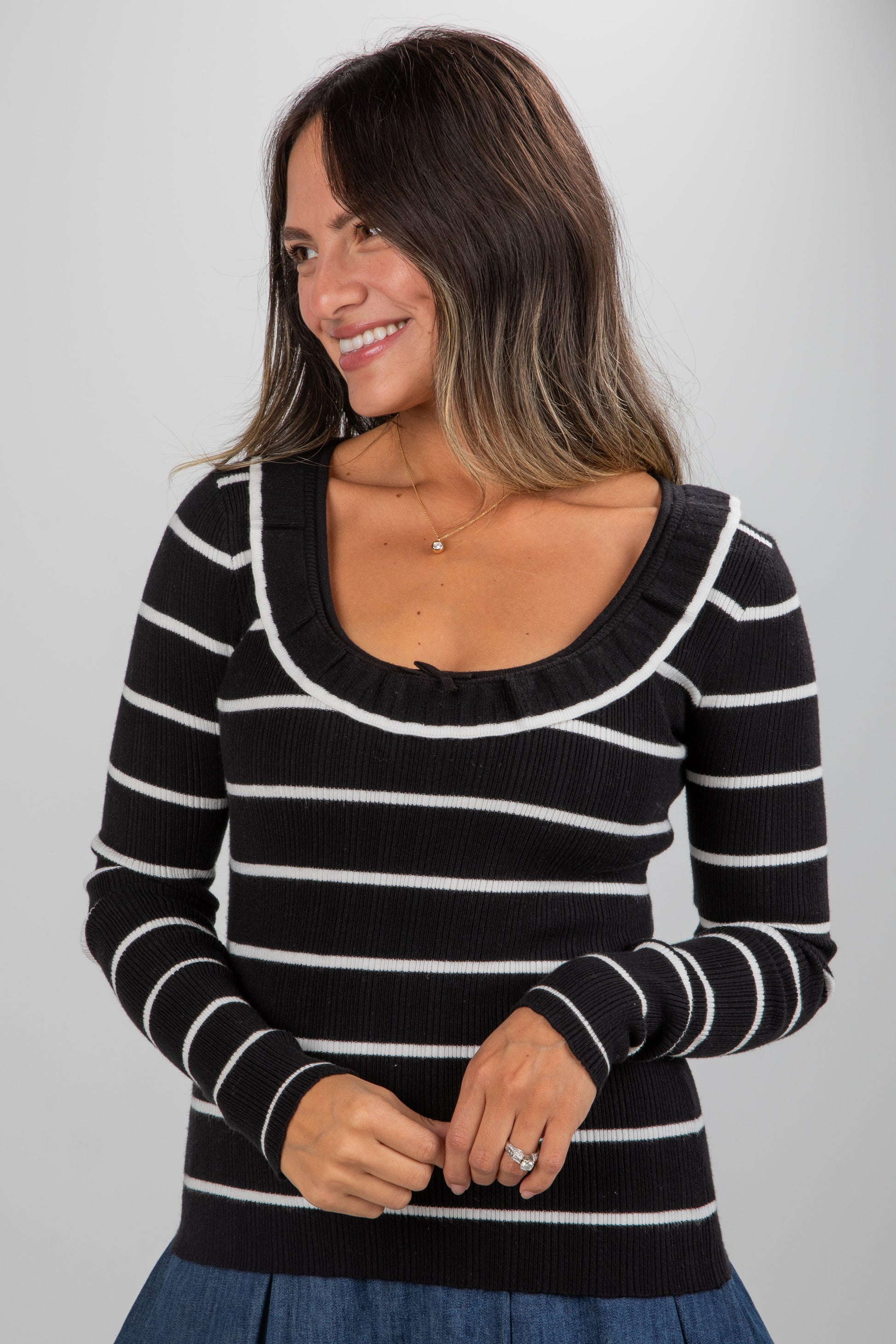 Woman wearing a black and white striped sweater against a plain background