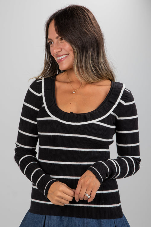 Woman wearing a black and white striped sweater against a plain background