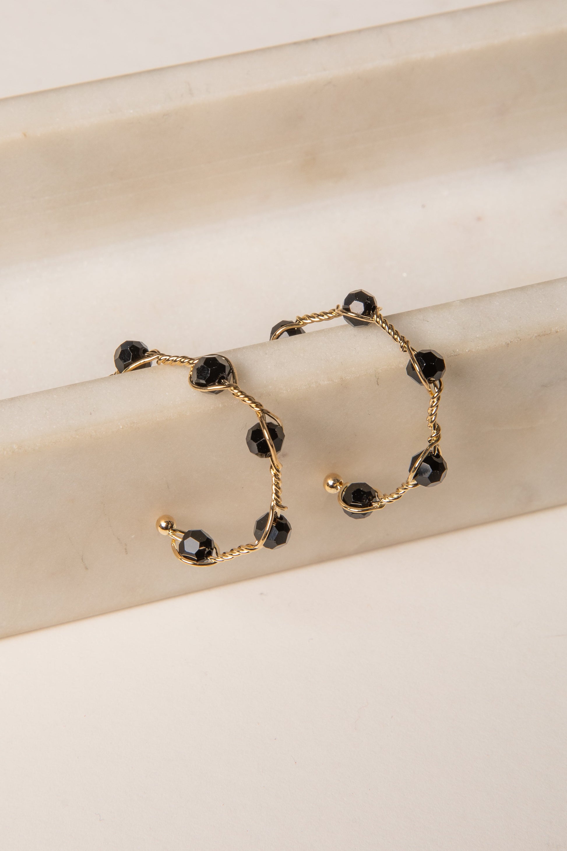Gold bracelet with black beads on a beige surface