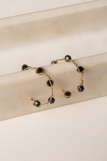 Gold bracelet with black beads on a beige surface