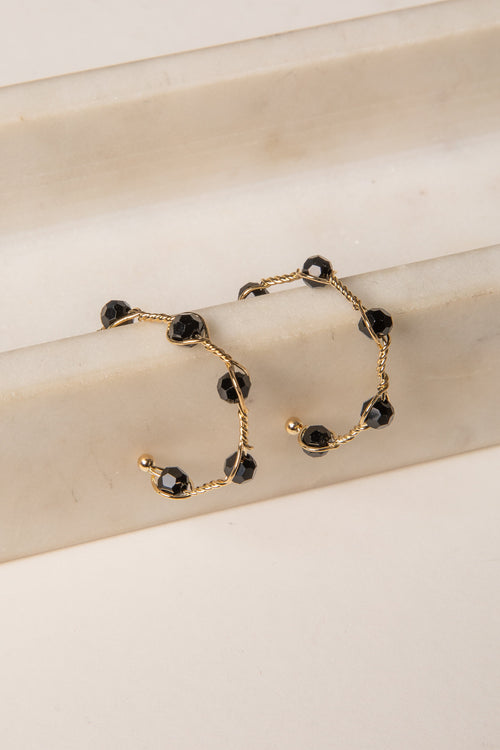 Gold bracelet with black beads on a beige surface