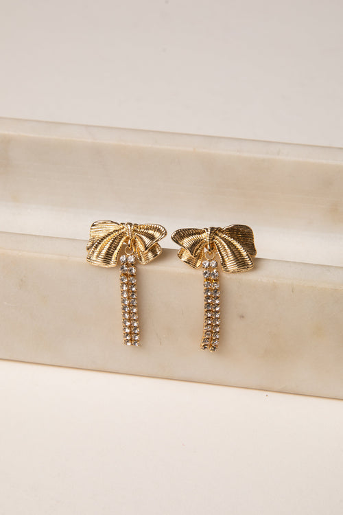 Gold earrings with tassel design on a beige surface