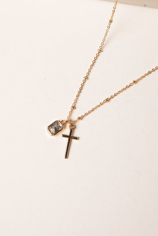 Gold necklace with a cross pendant on a white background