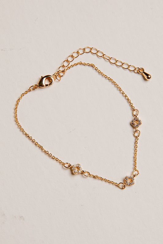 Gold bracelet with floral designs on a beige background