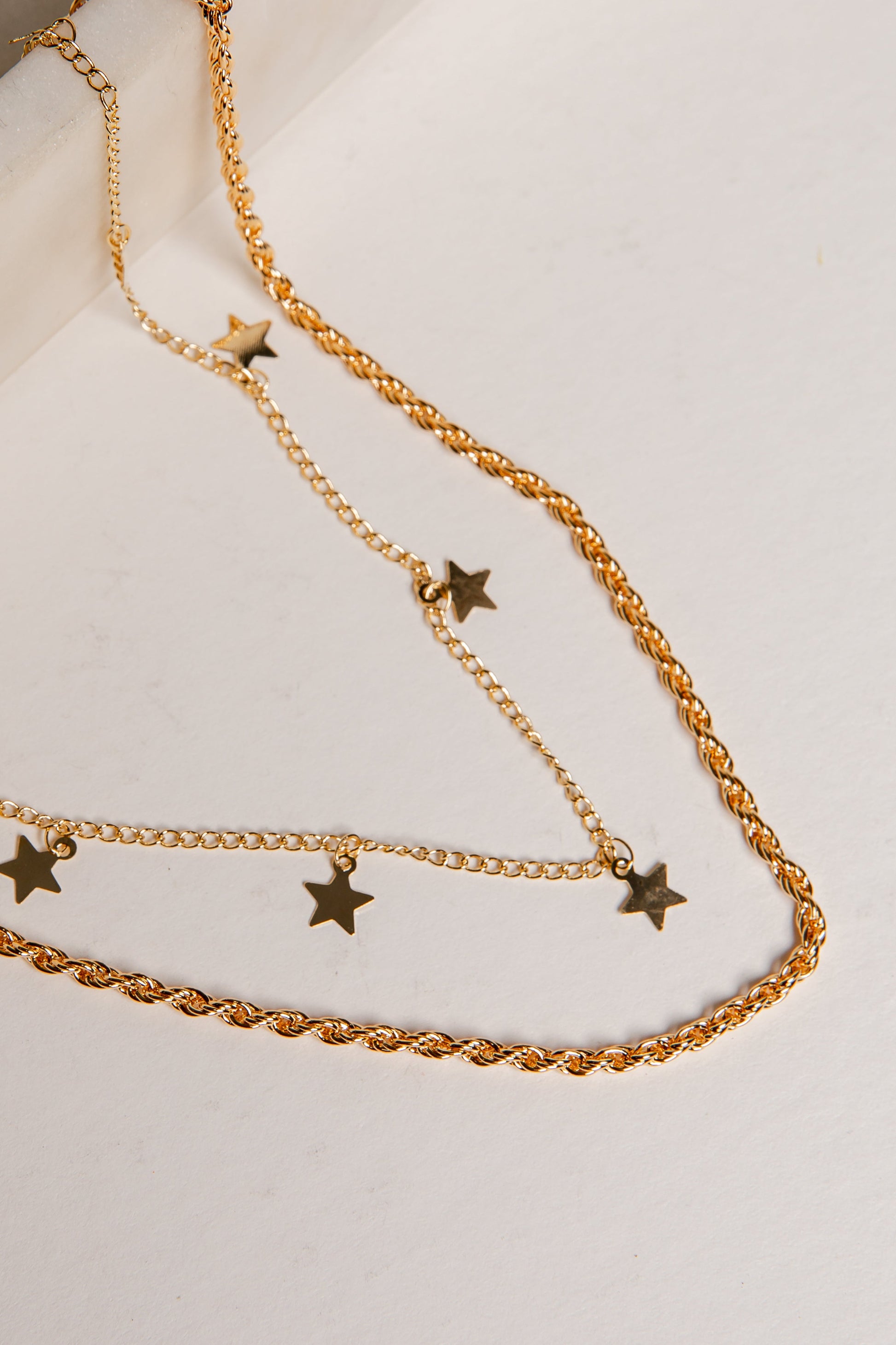 Gold chain necklace with star pendants on a light background