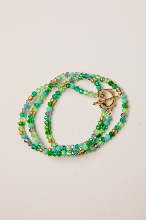 Multistrand beaded bracelet with a gold clasp on a beige background