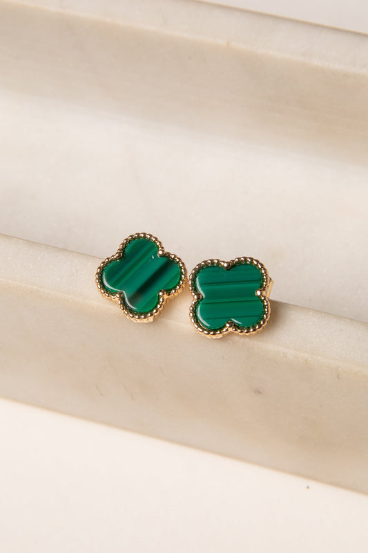 Green clover-shaped earrings on a beige surface
