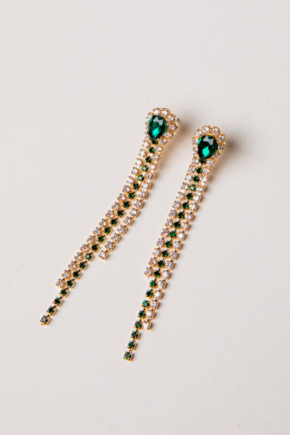 Pair of gold earrings with green gemstones on a light gray background