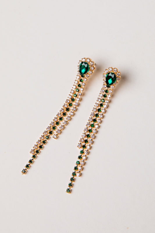 Pair of gold earrings with green gemstones on a light gray background