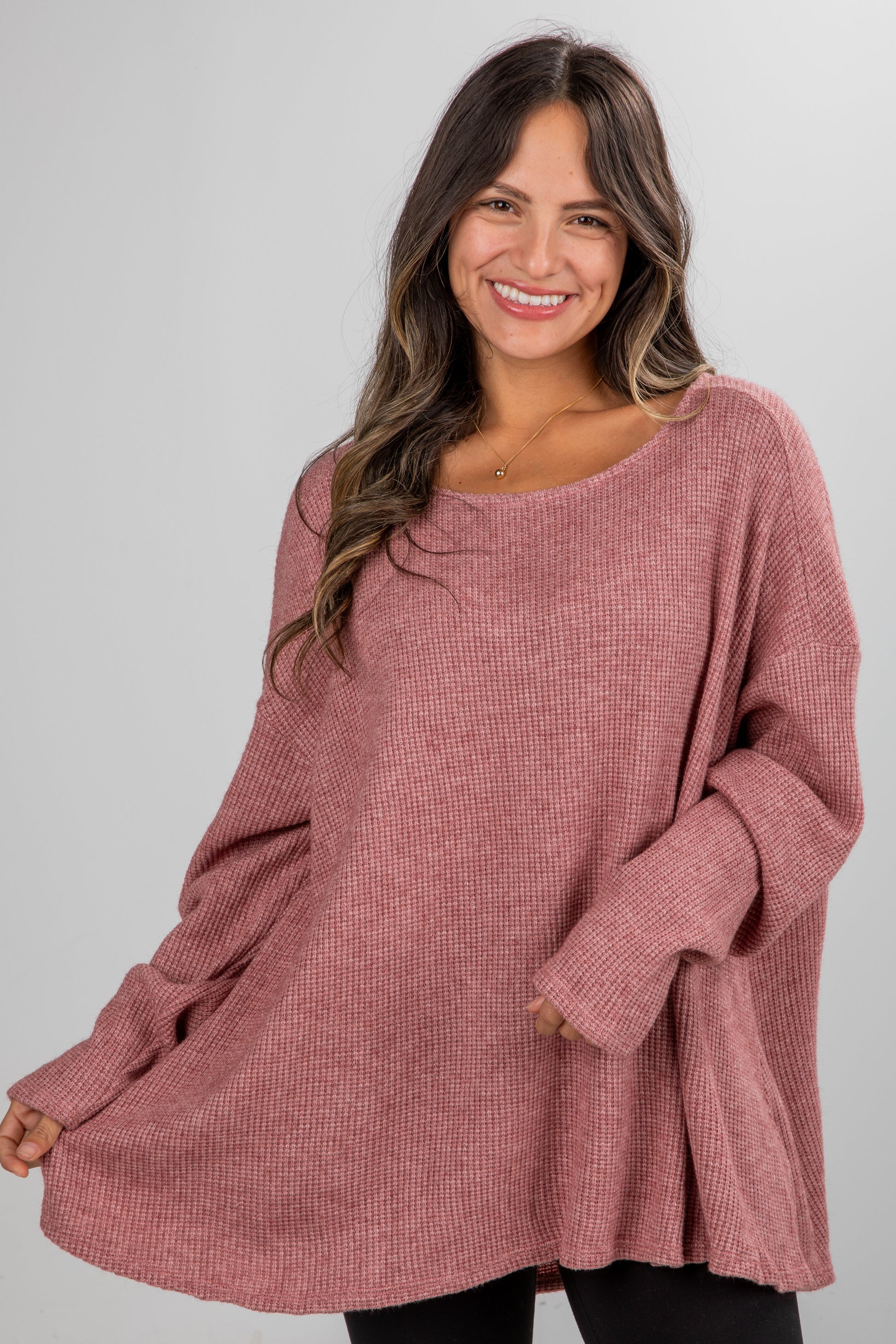 Woman wearing a pink sweater against a gray background