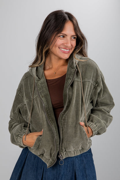 Woman wearing a green corduroy jacket on a gray background