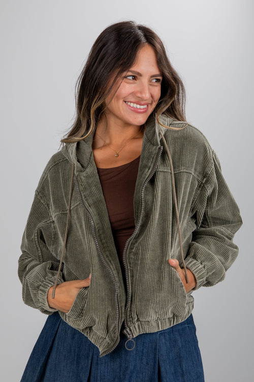 Woman wearing a green corduroy jacket on a gray background