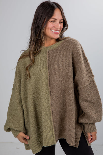 Woman wearing a two-tone sweater with green and brown sections on a plain background