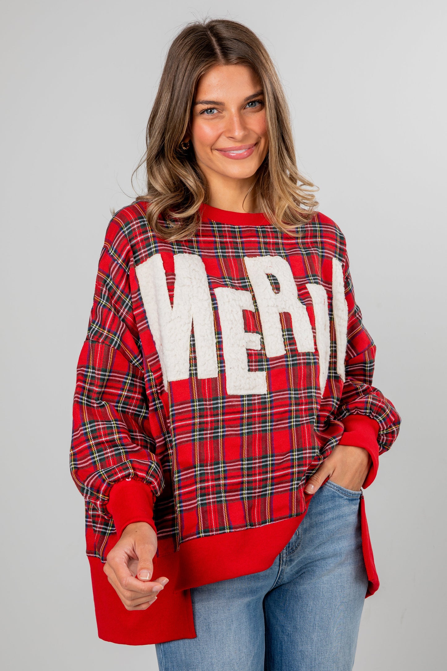 Woman wearing a red plaid sweater with 'Merry' text on a gray background