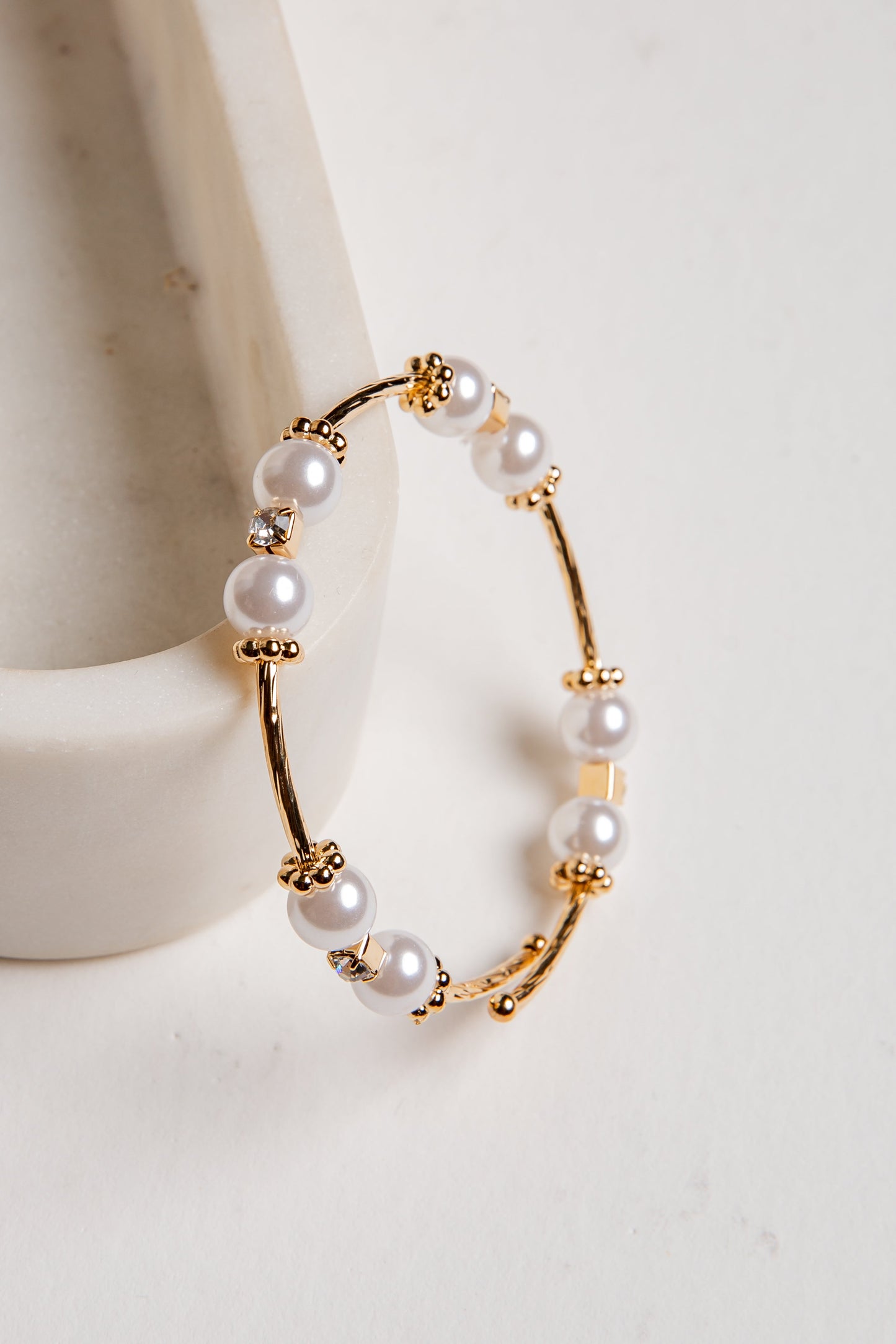 Gold hoop earrings with pearls on a white background
